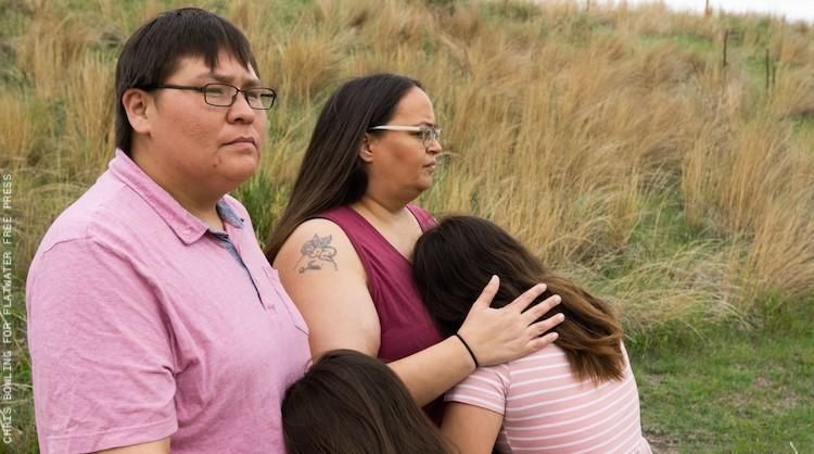 Four Lakota people on a grassy hill.