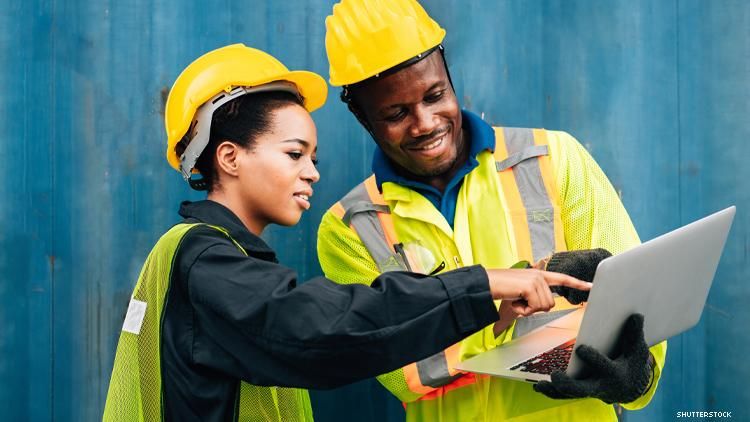 2 African American Workers in hard hats looking at computer