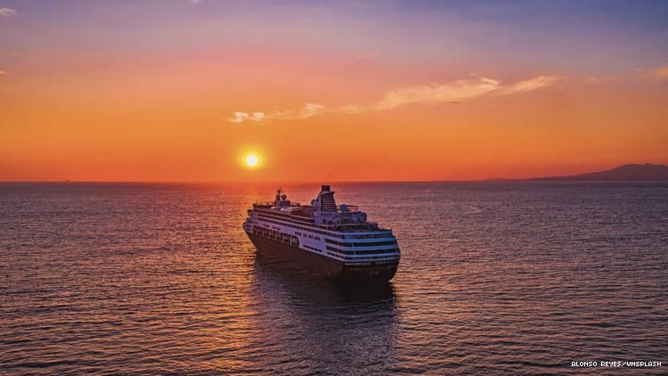 cruise ship on ocean with rising sun