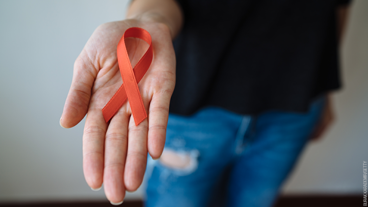 A man holds a red ribbon in his outstretched man