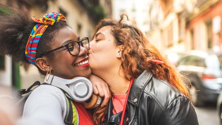 Women kissing other woman on the cheek