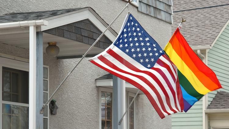 American flag and the Pride Flag on the porch of a house
