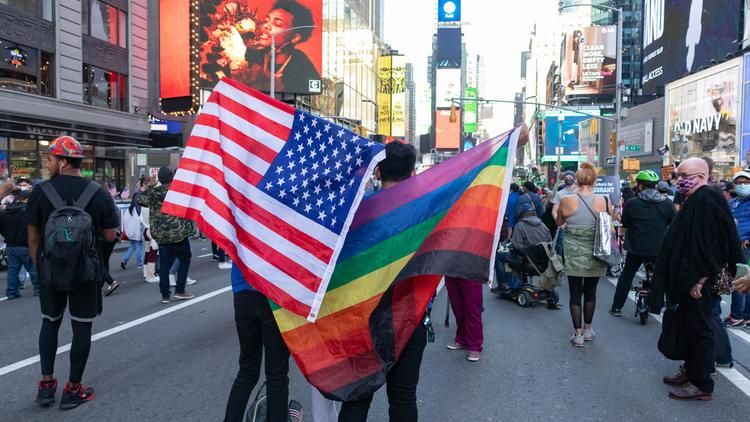 People holding American and Rainbow flags