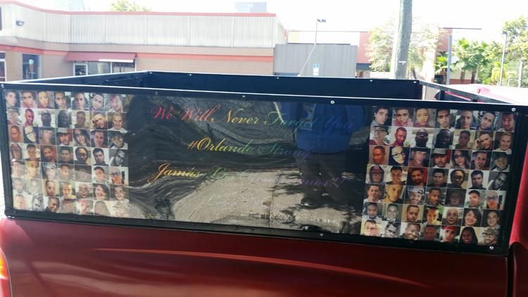 A nearby truck displays the faces of all 49 victims