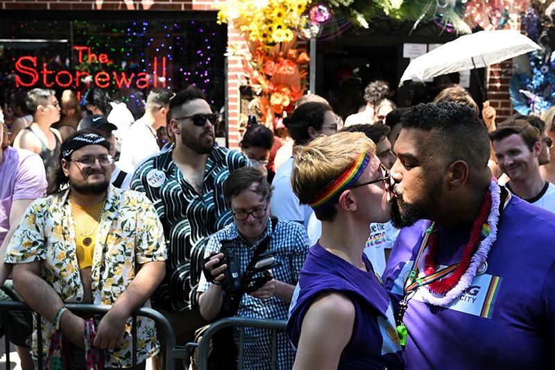 Ben Eisenstadt and Paul Staisiunas kiss for photographers in front of the historic Stonewall Inn at the New York City Pride Parade on June 26, 2022