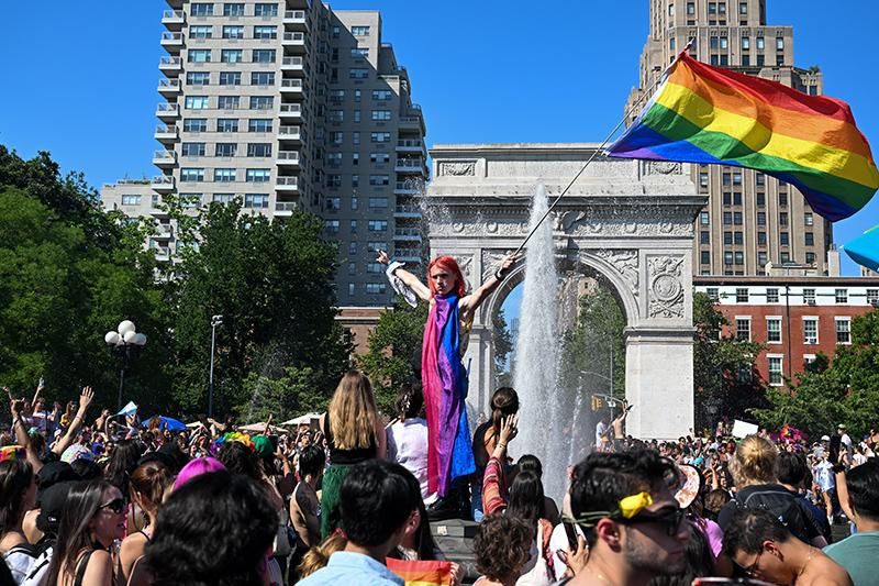 A person waves a Pride flag in the Washington Square Park fountain after the 4th Annual Queer Liberation March in New York City. This is a “people’s march” working to "reclaim the spirit and meaning of Pride” with a motto of "No Corps - No Cops - No BS"